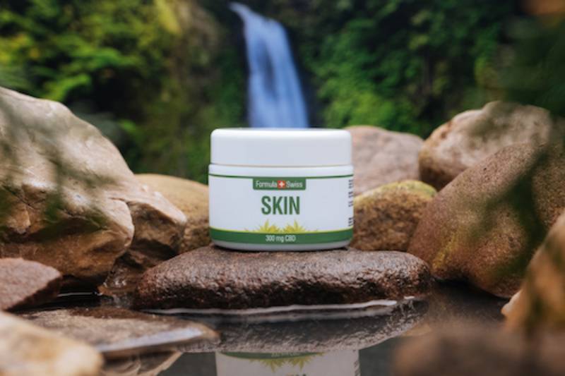 Krukke med Formula Swiss CBD Skin balm på en sten ved et vandfald